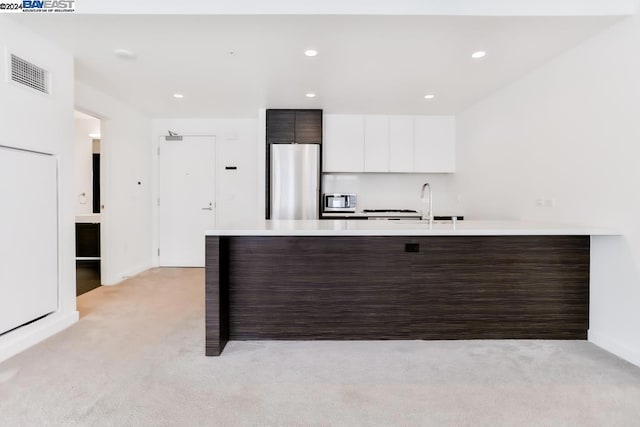 kitchen with dark brown cabinetry, light carpet, white cabinets, and stainless steel appliances