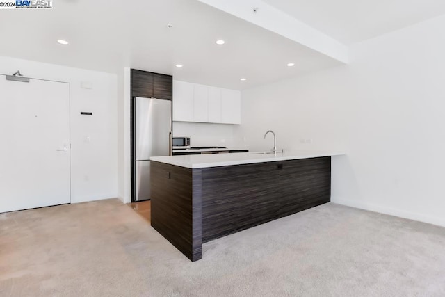 kitchen featuring dark brown cabinetry, white cabinetry, stainless steel appliances, and light carpet