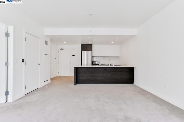 kitchen with white cabinets, stainless steel fridge, light colored carpet, and dark brown cabinetry