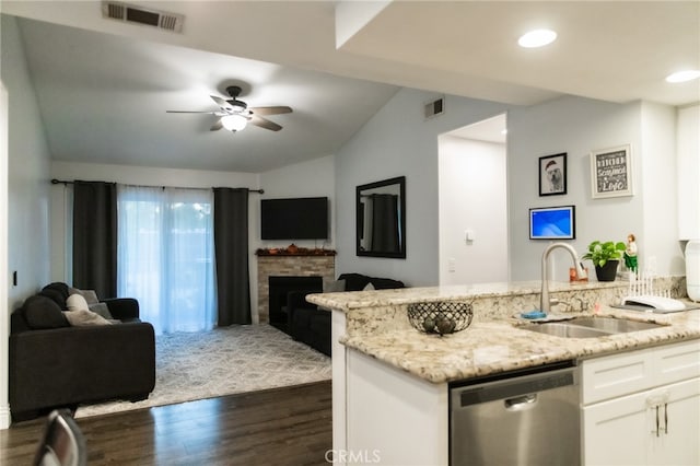 kitchen with dark hardwood / wood-style floors, white cabinets, vaulted ceiling, a fireplace, and stainless steel dishwasher