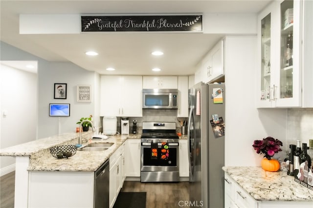 kitchen with light stone counters, white cabinets, sink, kitchen peninsula, and appliances with stainless steel finishes