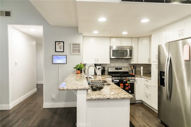 kitchen with appliances with stainless steel finishes, white cabinetry, kitchen peninsula, dark hardwood / wood-style flooring, and sink