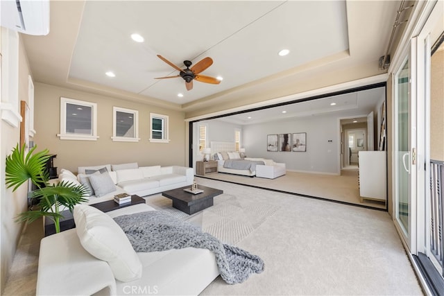 living room featuring carpet, a wall mounted air conditioner, a raised ceiling, and ceiling fan