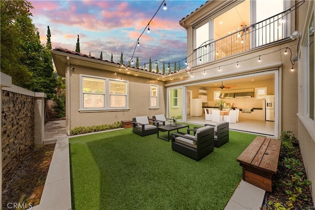 yard at dusk with an outdoor living space and a balcony