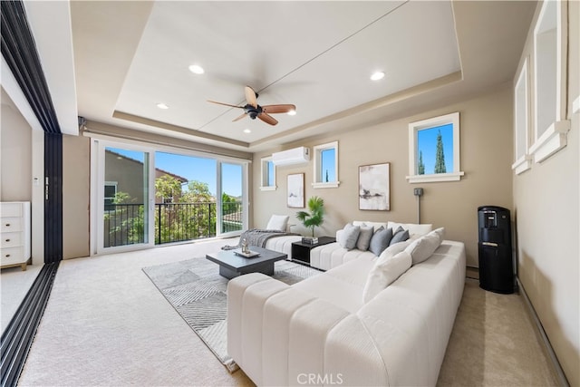 living room featuring a tray ceiling, a wall unit AC, ceiling fan, and light colored carpet