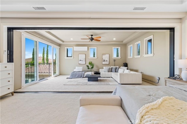 carpeted living room with ceiling fan, a wall unit AC, and a tray ceiling