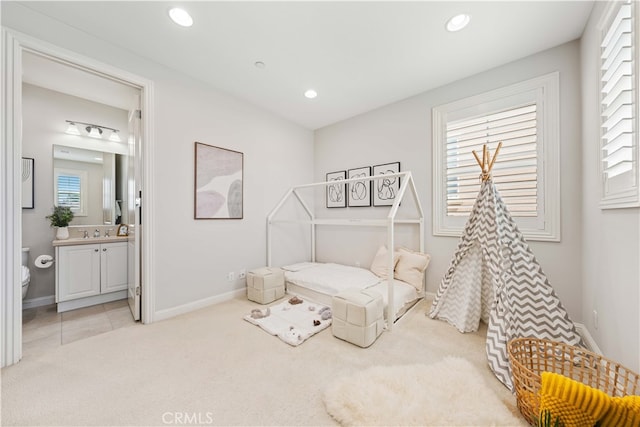 bedroom with sink, light carpet, and ensuite bath