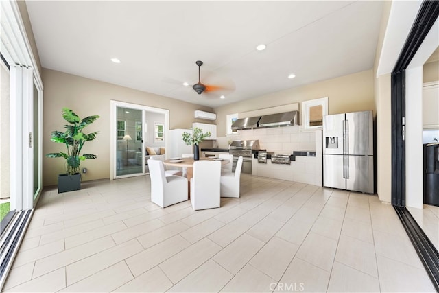 kitchen with range hood, a kitchen island, a healthy amount of sunlight, and stainless steel refrigerator with ice dispenser