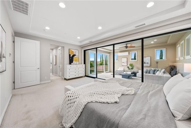 carpeted bedroom with access to outside and a tray ceiling