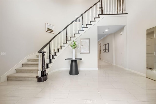 stairway with tile patterned floors, a towering ceiling, and crown molding