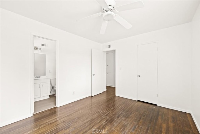 unfurnished bedroom featuring dark wood-type flooring, ensuite bathroom, sink, ceiling fan, and a closet