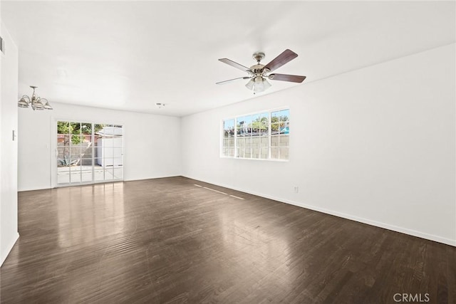 spare room featuring ceiling fan with notable chandelier and dark wood-type flooring