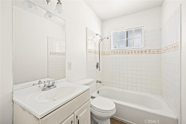 full bathroom featuring tiled shower / bath, vanity, and toilet