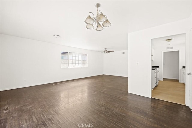 spare room featuring ceiling fan with notable chandelier and dark wood-type flooring