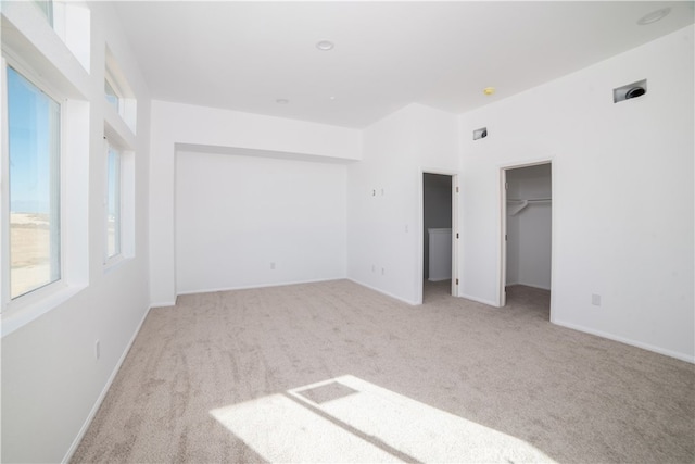 unfurnished bedroom featuring light carpet and a spacious closet