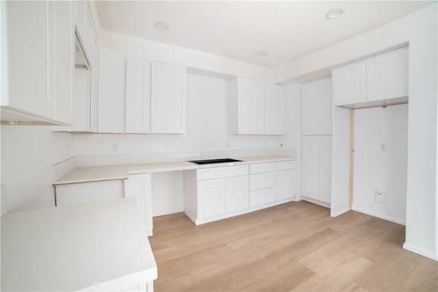 kitchen with light hardwood / wood-style flooring, white cabinetry, and black electric cooktop