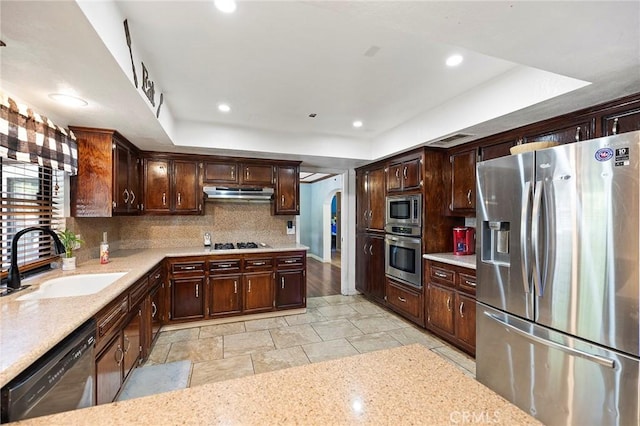 kitchen featuring backsplash, sink, a tray ceiling, and stainless steel appliances