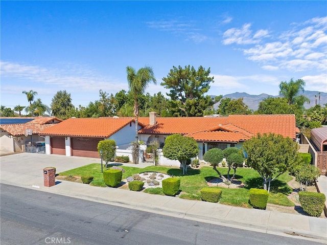 mediterranean / spanish house with a mountain view, a front lawn, and a garage