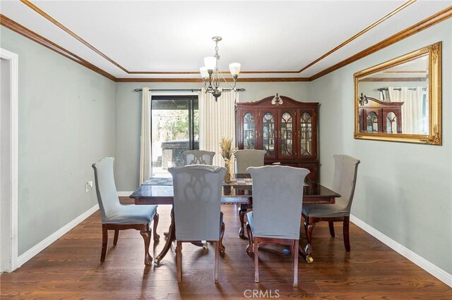 dining space with dark hardwood / wood-style floors, an inviting chandelier, and ornamental molding