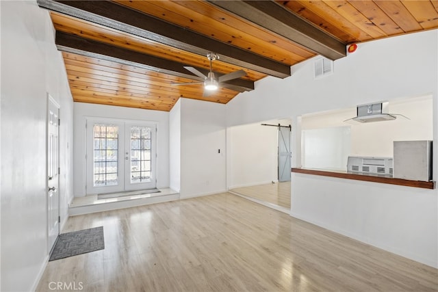 unfurnished living room featuring light hardwood / wood-style floors, lofted ceiling with beams, a barn door, wooden ceiling, and french doors