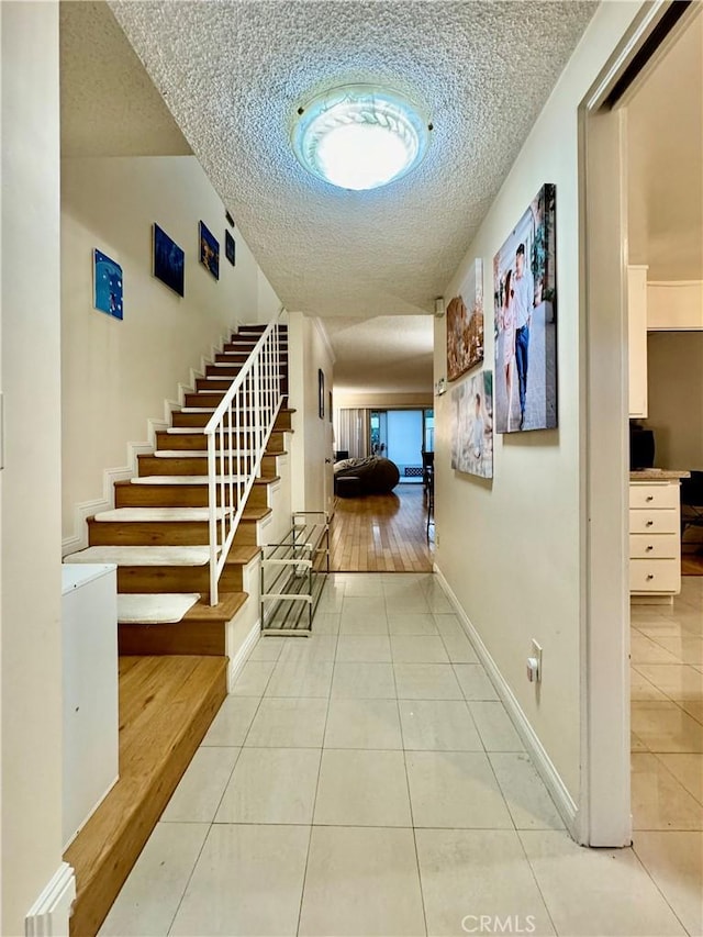 hall with a textured ceiling and light hardwood / wood-style floors