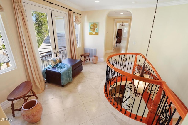 interior space with a chandelier, light tile patterned flooring, ornamental molding, and french doors