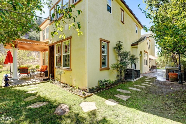 view of side of home featuring a pergola, a patio area, a yard, and central AC unit