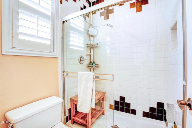 bathroom featuring toilet and a shower with shower door