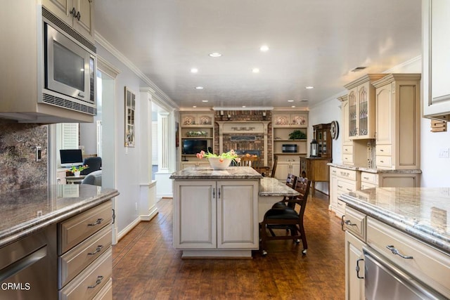 kitchen with stainless steel microwave, a center island, dark hardwood / wood-style floors, and ornamental molding