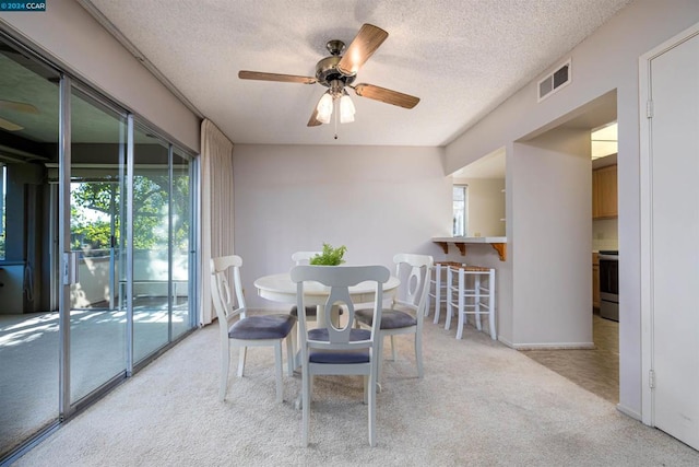 carpeted dining area featuring ceiling fan and a textured ceiling