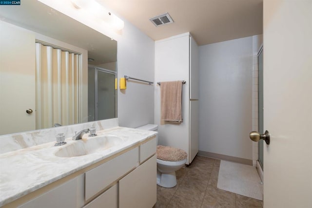 bathroom with a shower with door, tile patterned floors, vanity, and toilet