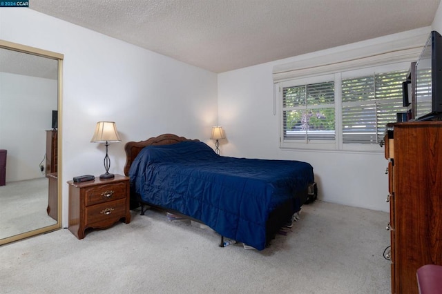 bedroom featuring light carpet and a textured ceiling