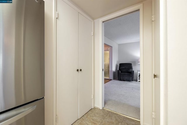 hallway featuring a textured ceiling and light colored carpet