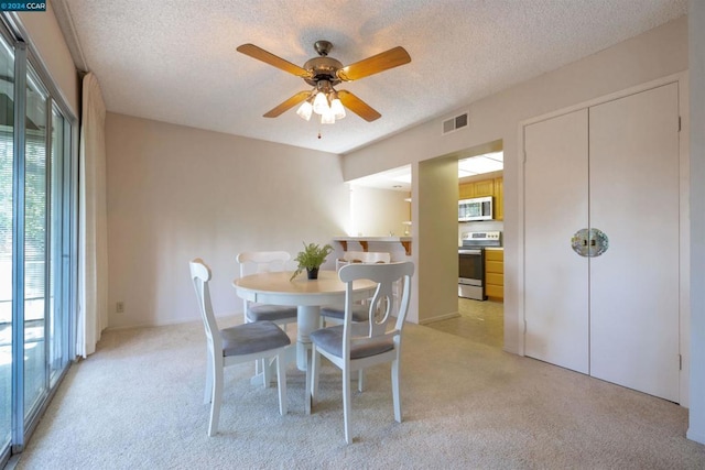 carpeted dining space with ceiling fan and a textured ceiling