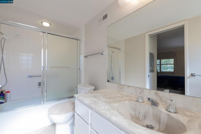 full bathroom with vanity, bath / shower combo with glass door, and toilet