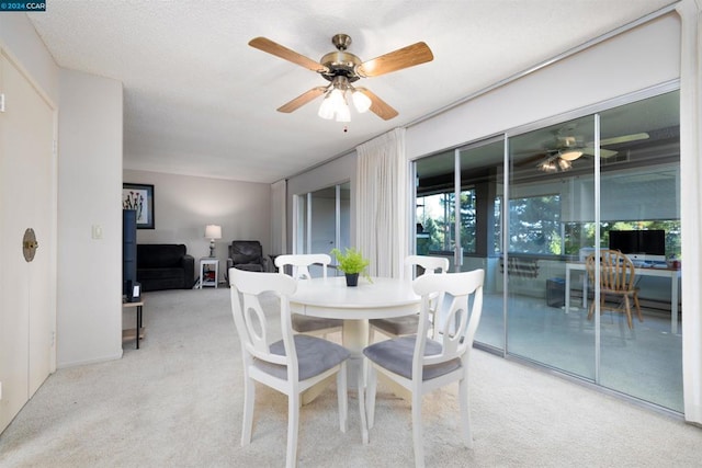 dining space featuring ceiling fan and light colored carpet