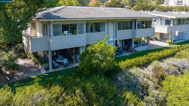 rear view of house with a balcony and a lawn