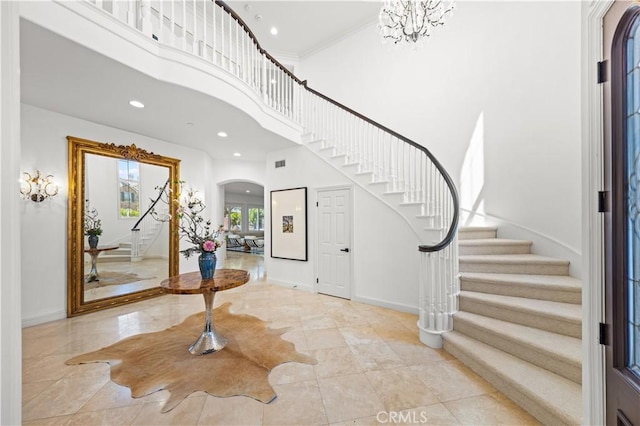 entrance foyer with a notable chandelier, crown molding, and a high ceiling