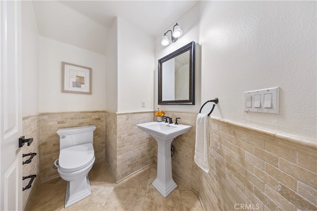 bathroom with tile patterned floors, tile walls, and toilet