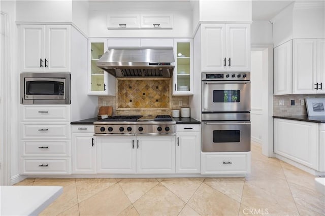 kitchen with ventilation hood, white cabinets, decorative backsplash, light tile patterned floors, and appliances with stainless steel finishes