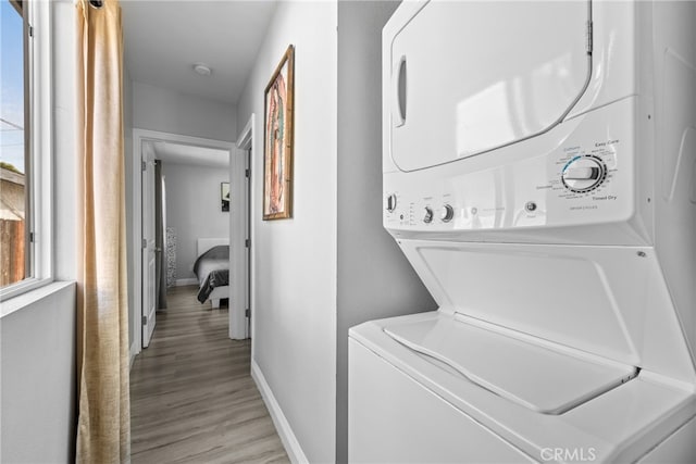 laundry room featuring light wood-type flooring and stacked washer and dryer