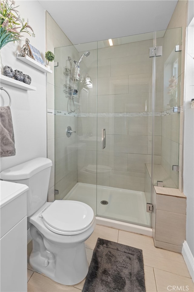 bathroom featuring tile patterned flooring, a shower with door, vanity, and toilet