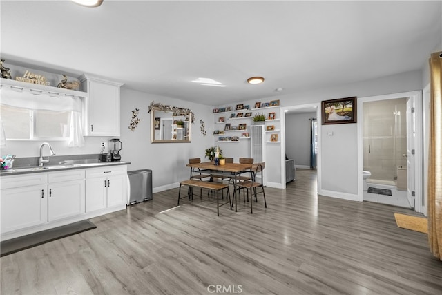 kitchen featuring light wood-type flooring, white cabinetry, and sink