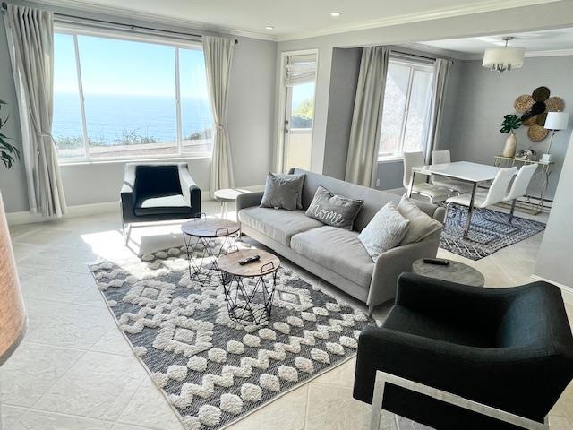 living room featuring a notable chandelier, crown molding, a water view, and light tile patterned flooring