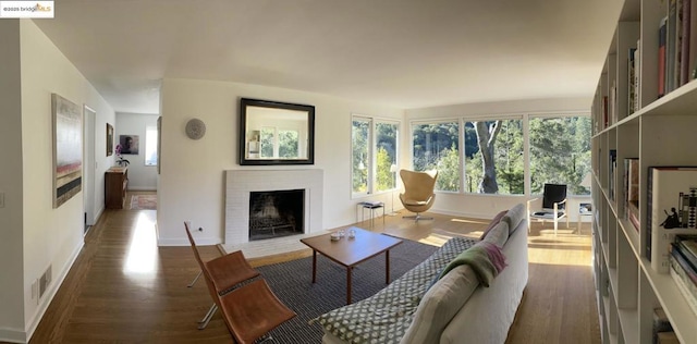 living room with a brick fireplace and dark wood-type flooring