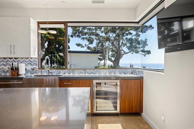 bar with tasteful backsplash, a healthy amount of sunlight, decorative light fixtures, white cabinets, and wine cooler