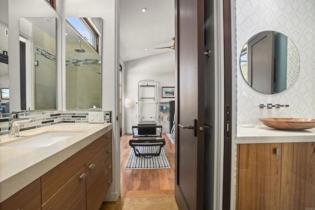 bathroom featuring tasteful backsplash, walk in shower, vanity, vaulted ceiling, and wood-type flooring