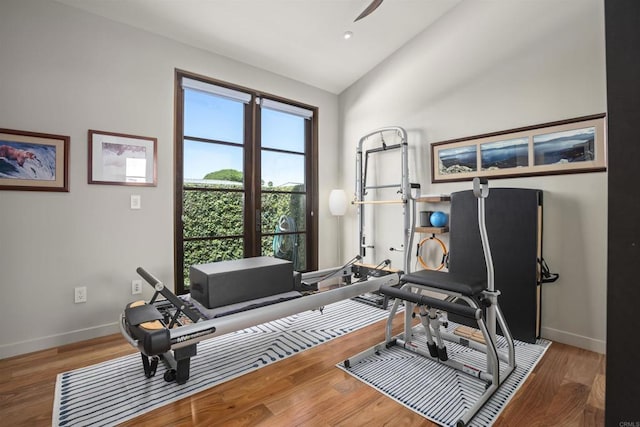 exercise room with hardwood / wood-style flooring, ceiling fan, and vaulted ceiling