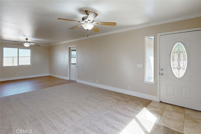 carpeted foyer entrance with ceiling fan, a healthy amount of sunlight, and crown molding