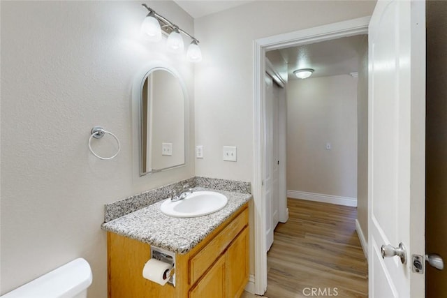 bathroom with toilet, hardwood / wood-style floors, and vanity